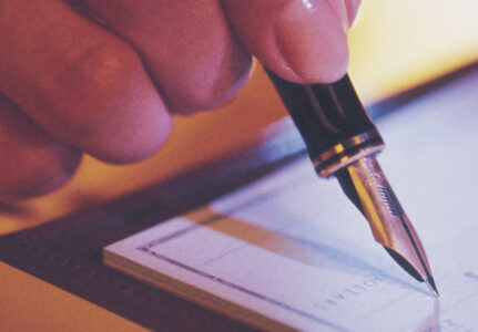 article image - Hand of person writing a check